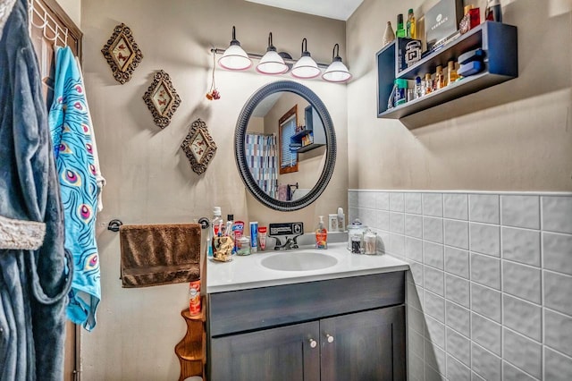 full bathroom featuring a wainscoted wall, vanity, and tile walls