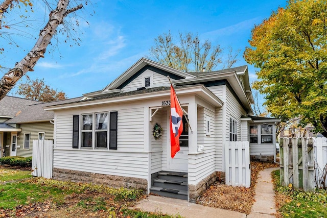 bungalow featuring entry steps and fence