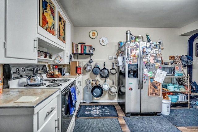 kitchen with range with electric cooktop, wood finished floors, white cabinetry, light countertops, and stainless steel fridge