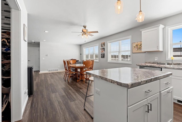 kitchen featuring baseboards, white cabinets, visible vents, dark wood finished floors, and a center island