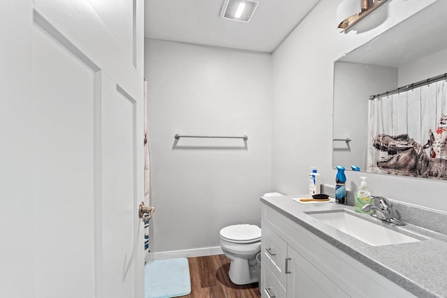 bathroom with toilet, wood finished floors, visible vents, vanity, and baseboards