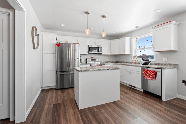 kitchen with white cabinets, appliances with stainless steel finishes, a center island, dark wood finished floors, and pendant lighting