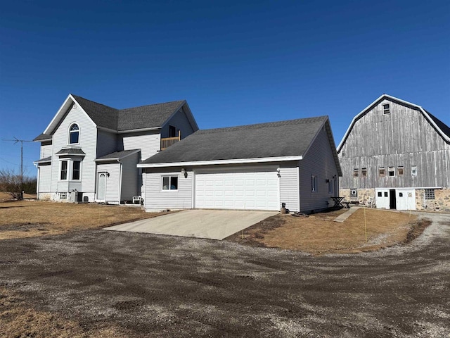 view of front facade with a barn, an attached garage, concrete driveway, and an outdoor structure