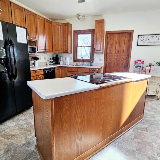 kitchen featuring black appliances, a sink, light countertops, and brown cabinets