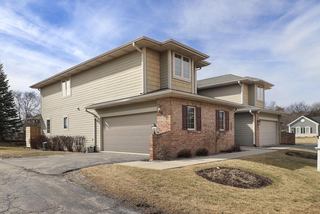 view of side of property with a yard, driveway, brick siding, and an attached garage