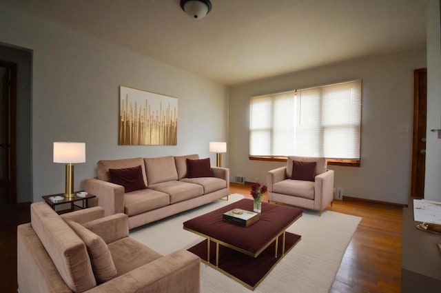 living area with wood finished floors, visible vents, and baseboards