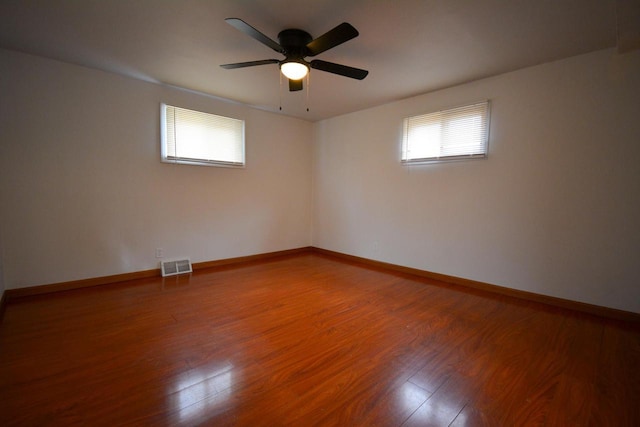 spare room featuring visible vents, ceiling fan, baseboards, and wood finished floors