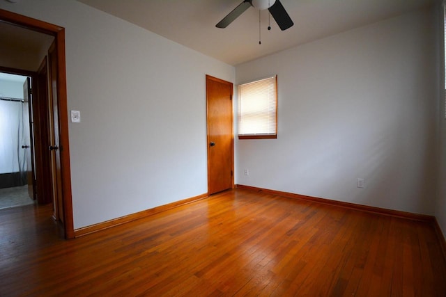 empty room featuring a ceiling fan, baseboards, and hardwood / wood-style floors