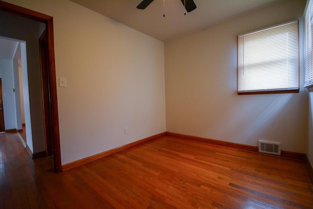 empty room featuring baseboards, visible vents, ceiling fan, and wood finished floors