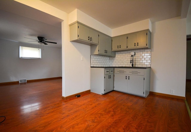 kitchen featuring dark countertops, visible vents, backsplash, dark wood-type flooring, and baseboards