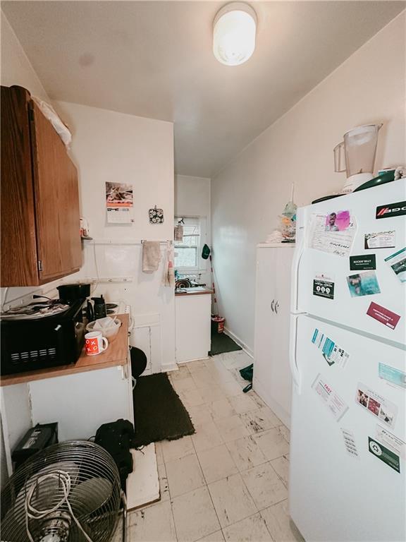 kitchen with brown cabinets and freestanding refrigerator