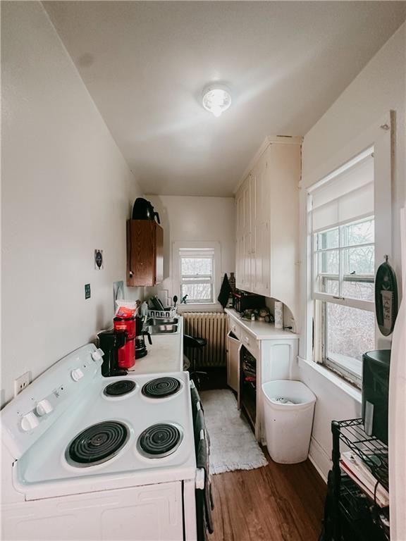 kitchen featuring radiator, light wood finished floors, white electric stove, and light countertops