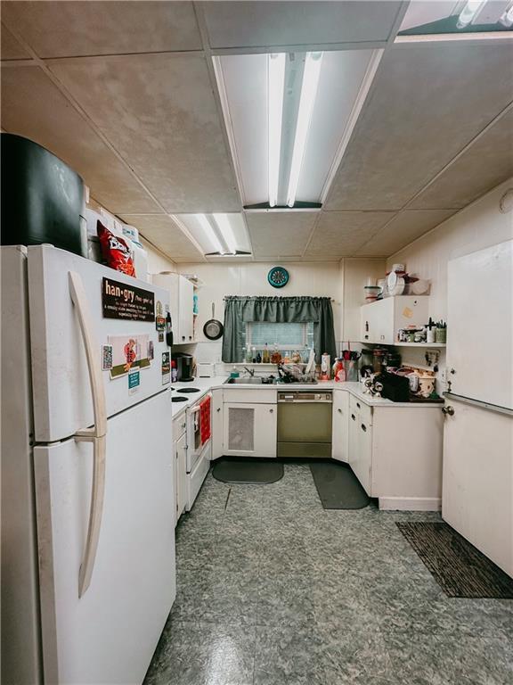 kitchen featuring white appliances, dark floors, white cabinets, and light countertops