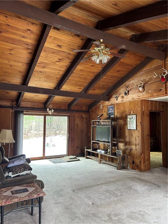 unfurnished living room featuring carpet floors, wood ceiling, wooden walls, and lofted ceiling with beams