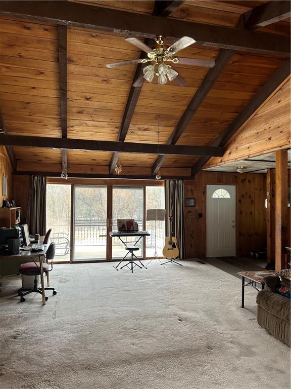 carpeted living area with lofted ceiling with beams, plenty of natural light, wooden walls, and wood ceiling