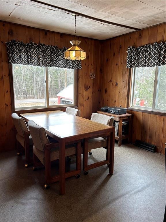 dining room featuring light carpet and wooden walls