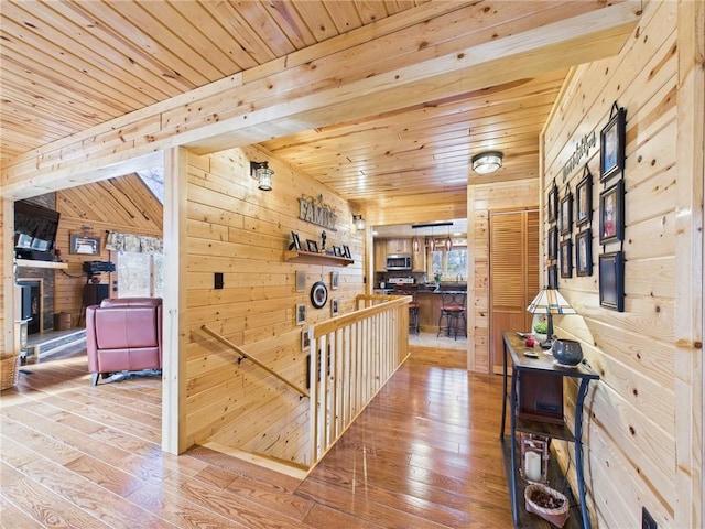 hall featuring a wealth of natural light, wooden ceiling, wood walls, and light wood-style flooring