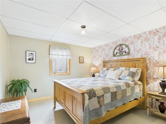 bedroom with wallpapered walls, baseboards, and a drop ceiling