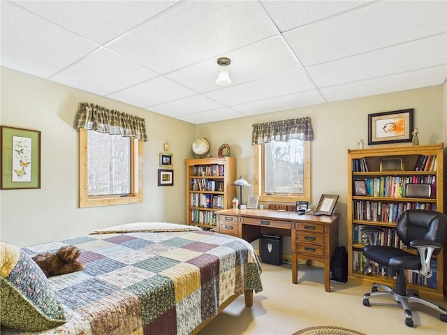 bedroom featuring light carpet and a drop ceiling