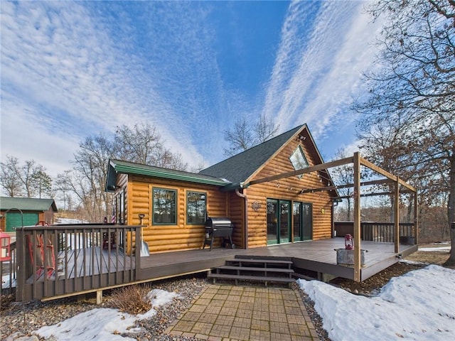 snow covered back of property with faux log siding and a wooden deck