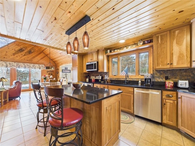 kitchen with light tile patterned floors, lofted ceiling, a sink, appliances with stainless steel finishes, and decorative backsplash