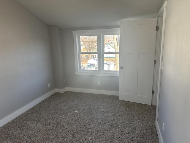 empty room featuring carpet and baseboards