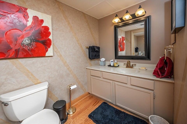 half bathroom with vanity, toilet, and wood finished floors