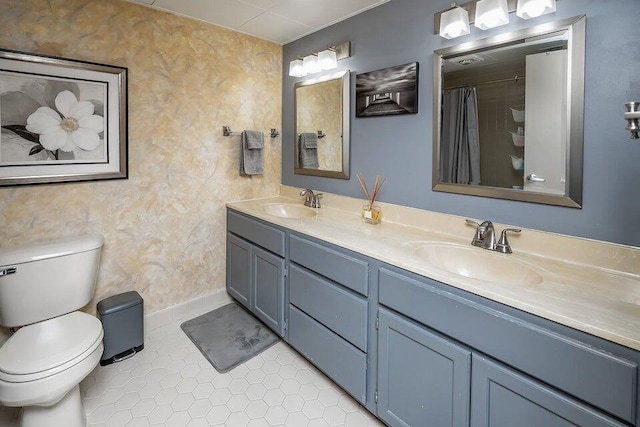 bathroom with double vanity, tile patterned flooring, a sink, and toilet