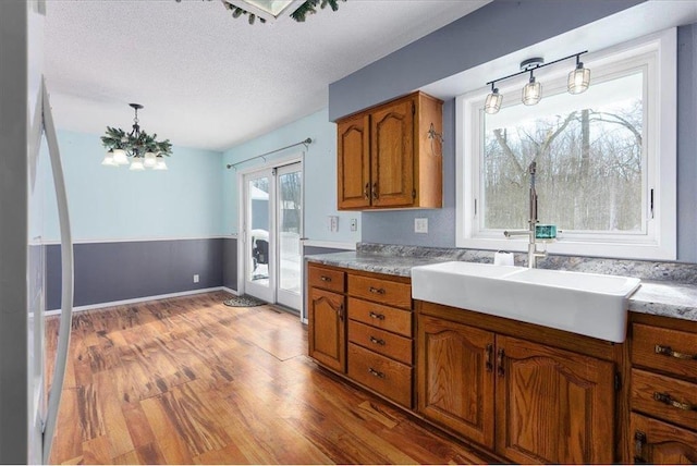 kitchen featuring a textured ceiling, a sink, light wood-style floors, light countertops, and brown cabinetry