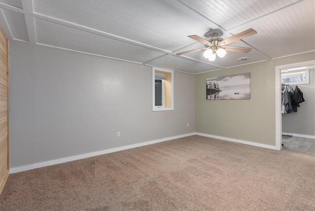 carpeted spare room with a ceiling fan and baseboards