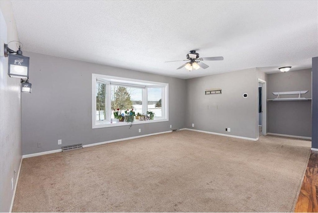 spare room with carpet, visible vents, a textured ceiling, and baseboards