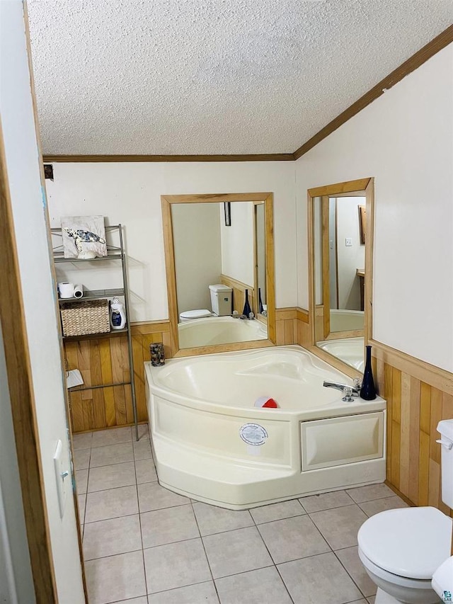 bathroom with tile patterned flooring, wainscoting, a textured ceiling, and toilet