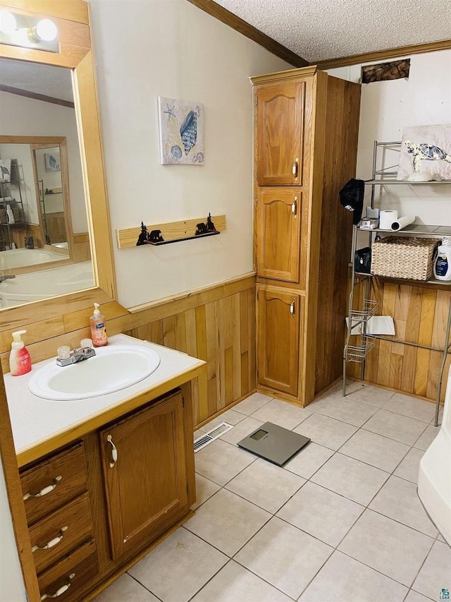 bathroom with a wainscoted wall, crown molding, wood walls, a textured ceiling, and vanity