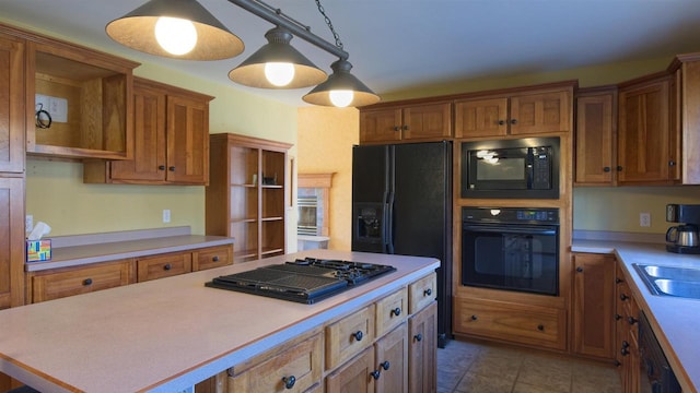 kitchen with brown cabinetry, a center island, tile patterned floors, light countertops, and black appliances