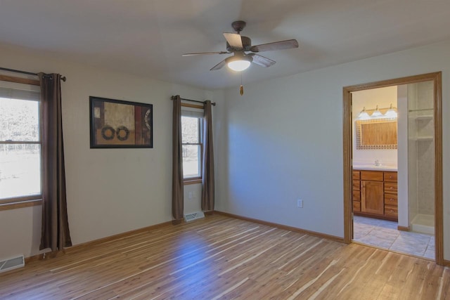 unfurnished bedroom with light wood finished floors, ensuite bath, visible vents, and ceiling fan