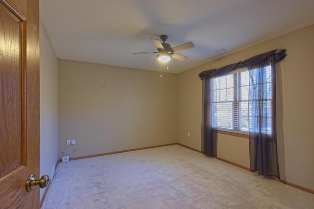 unfurnished room with light carpet, a ceiling fan, and baseboards