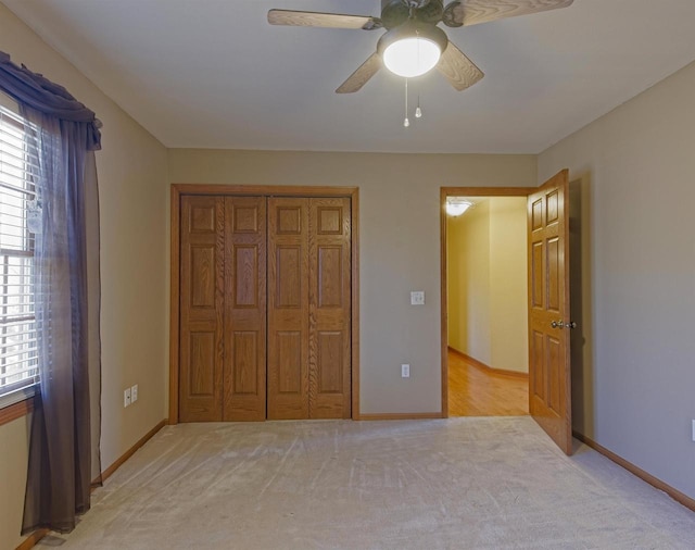 unfurnished bedroom with a closet, light carpet, ceiling fan, and baseboards