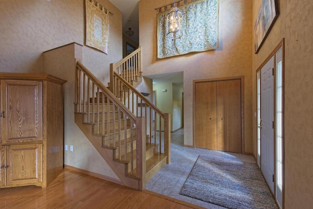 foyer entrance with a chandelier, a high ceiling, wood finished floors, baseboards, and stairs