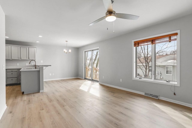 interior space with baseboards, visible vents, decorative light fixtures, light countertops, and light wood-style floors