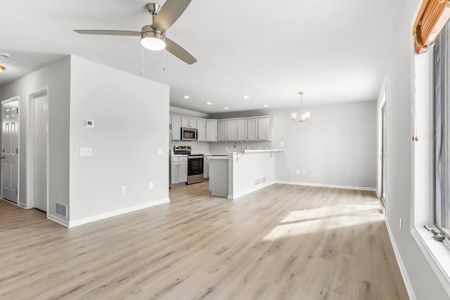 unfurnished living room with recessed lighting, visible vents, baseboards, light wood-type flooring, and ceiling fan with notable chandelier