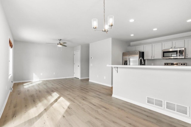 kitchen with light wood finished floors, light countertops, visible vents, appliances with stainless steel finishes, and ceiling fan with notable chandelier