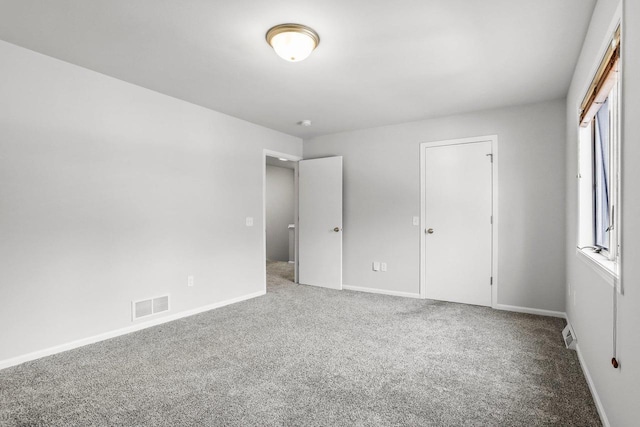 unfurnished bedroom featuring carpet, multiple windows, visible vents, and baseboards