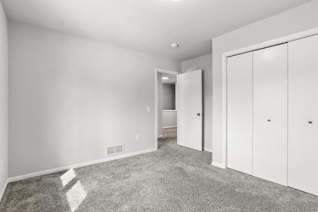 unfurnished bedroom with carpet floors, baseboards, visible vents, and a closet