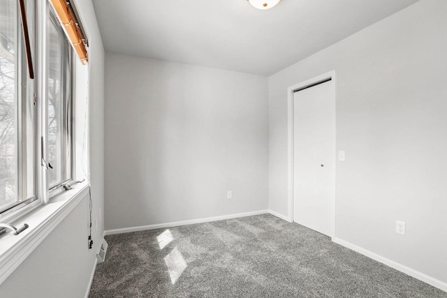 carpeted spare room featuring baseboards