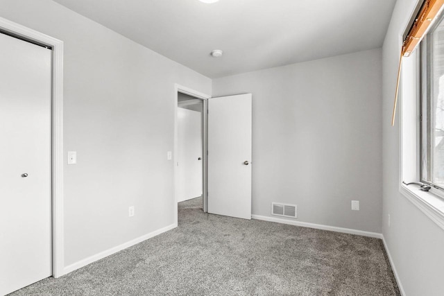 unfurnished bedroom featuring carpet, visible vents, and baseboards