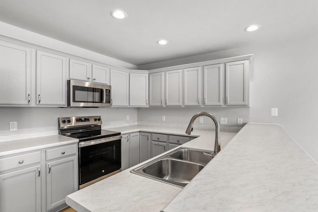 kitchen featuring appliances with stainless steel finishes, recessed lighting, light countertops, and a sink