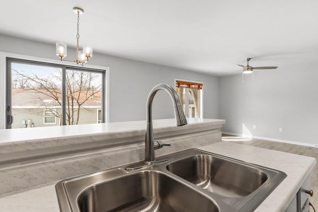 room details featuring light countertops, pendant lighting, a sink, and wood finished floors