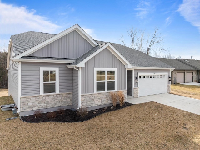 view of front of house featuring roof with shingles, an attached garage, board and batten siding, stone siding, and driveway