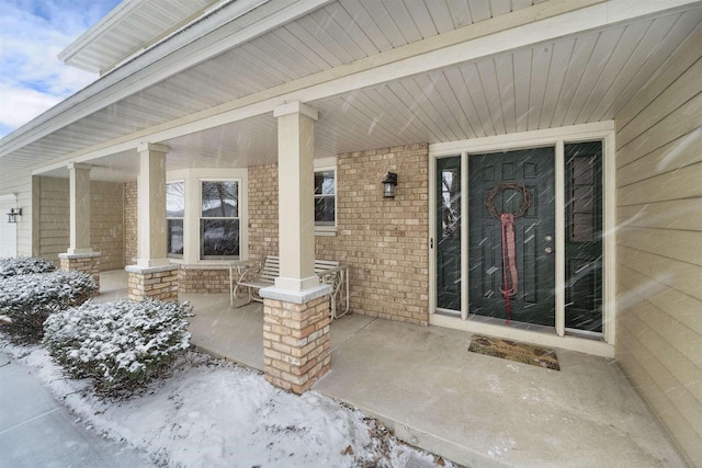 entrance to property with a porch and brick siding