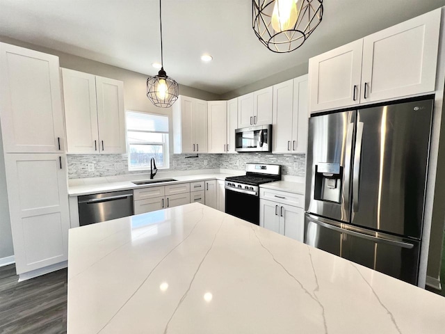 kitchen with a sink, light stone countertops, stainless steel appliances, white cabinetry, and backsplash